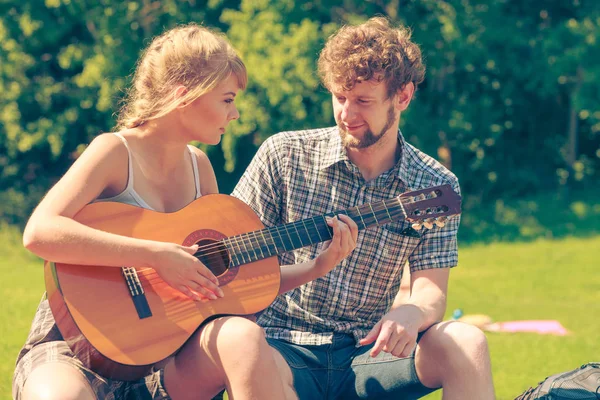 Macera, turizm, yaz tatilinin tadını çıkarmak. Genç bir çift kampta gitar çalarken eğleniyor.