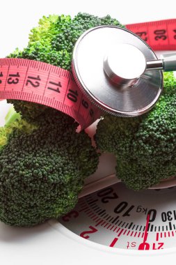 Diyet sağlıklı beslenme kilo kontrolü kavramı. Ölçme bant ve beyaz ölçeklerde stetoskop ile portre yeşil brokoli
