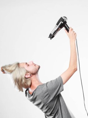 Saç modeli ve moda. Genç moda erkek kuaförü Kuaför göz değişen yeni fikir. Sarışın adam saç kurutma makinesi tutan ve tarak yeni saç modeli oluşturma