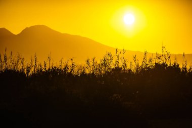 Dağ tepe üzerinde yükselen doğal gündoğumu veya günbatımı güneş