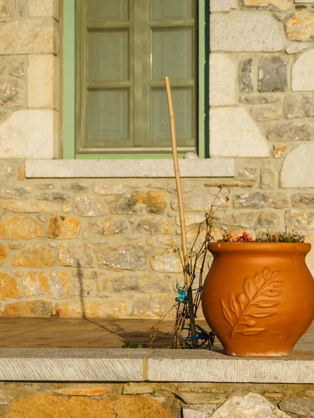 Big vase flowerpot against home wall and window in mediterranean style of architecture