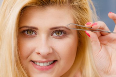 Kaşlarını yolan bir kadın cımbızla tükendi. Yüzünün bir kısmını kapatıyordu. Cımbızla yüz kıllarını kesen kız...