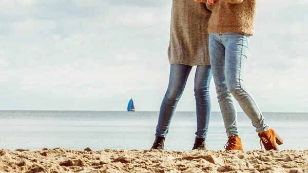 Осенняя женская обувь. Женщины в синих джинсах и стильных осенних ботинках прогуливаются по пляжу. Обувь идеально подходит для зимы
.