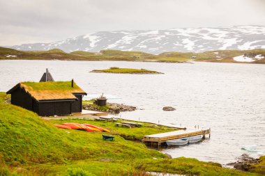 Lodge Haukeliseter Fjellstue, evler çatı üzerinde büyüyen çimen ile. Birçok Kano açık, Norveç göl manzara.