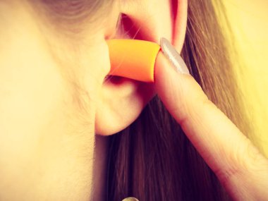 Yüksek sesle yerinde gürültü kurtulmak onun kulaklarına kadın koyarak kulak tıkacı.