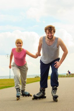 Aktif yaşam tarzı ve özgürlük kavramı. Deniz kıyısında paten süren genç ve zinde bir çift, kadın ve erkek birlikte vakit geçiriyorlar..