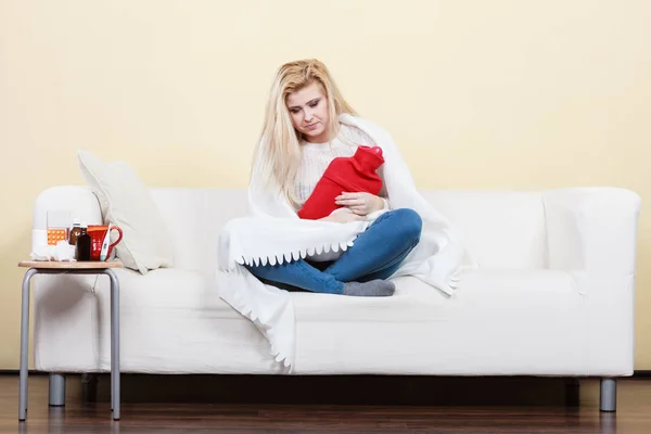 季节性病毒问题概念 女人生病了流感躺在沙发上拥抱热水壶 — 图库照片