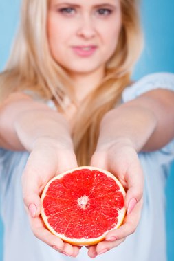 Kadın gülümseyen kız kırmızı greyfurt yarısı elinde mavi narenciye meyve tutan. Sağlıklı bir diyet yemek. Yaz tatil kavramı.