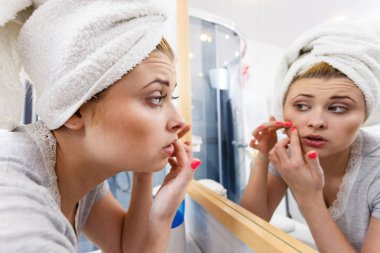 Yansıması hakkında ciddi bir yüz ifadesi, sahip onun kompleksleri ayna düşüncesinde bakarak kadın yüz cilt cilt sivilce sıkma analiz