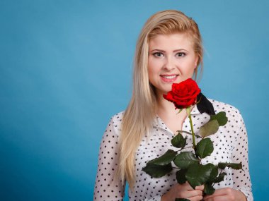 Kadın holding kırmızı gül. Güzel sarışın gülümseyen kız çiçek studio ile mavi vurdu. Romantizm, özel günler, Sevgililer günü kavramı