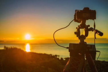 Professional camera taking picture film video of sunrise over sea surface, Greece Peloponnese. clipart