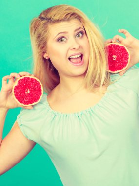 Kadın gülümseyen kız kırmızı greyfurt iki halfs narenciye meyve ellerinde yeşil holding. Sağlıklı bir diyet yemek. Yaz tatil kavramı eğlenceli.