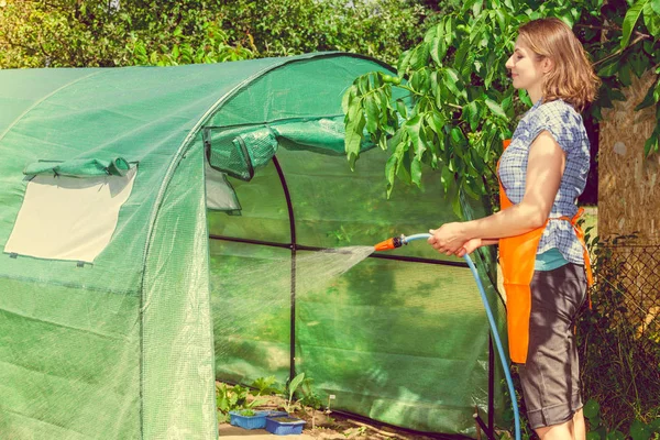 Berkebun Perempuan Celemek Oranye Memegang Selang Sprinkler Untuk Irigasi Tanaman — Stok Foto