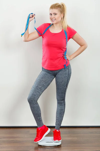 健康生活スタイル 制御体コンセプトに合わせて スポーツウェア レギンス 重量機械保持測定テープの上に立ってのトレーナーを着ている女性 — ストック写真