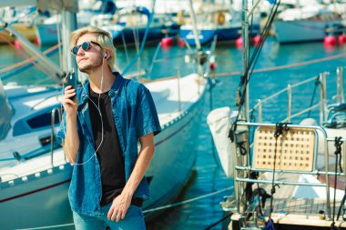 Tatil, dinlenme, tutku kavramı. Loudspeeker sistemi ile telefonda konuşuyor ve güzel, güneşli havanın tadını güneş gözlüğü adam sarışın genç moda. Açık atış