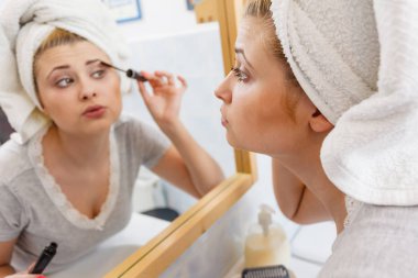 Visage ve makyaj kavramı. Kadın banyoda havlu maskara kirpik üzerinde uygulama kafasına takmış