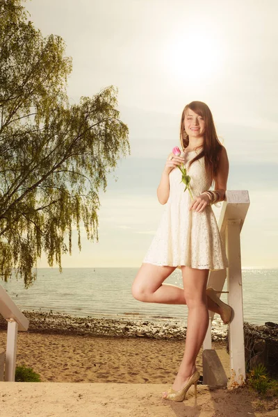 喜びの概念 ピンクのチューリップとビーチでの自由時間を支出を保持短い白いドレスを着ている女性 背景の海 — ストック写真