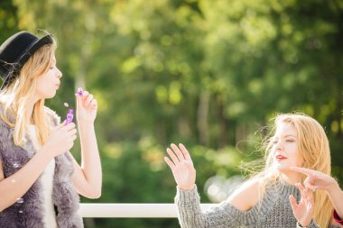 Tatil eğlencesi, arkadaşlık konsepti. Kadın arkadaşlar dışarıda sabun köpüğü üflerken eğleniyorlar..
