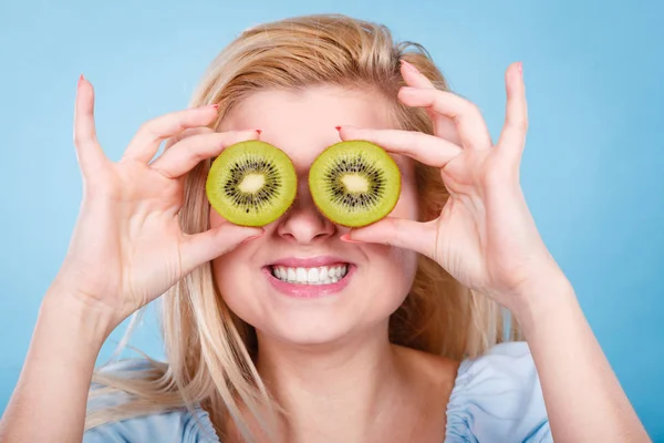 Healthy diet, refreshing food full of vitamins. Woman holding sweet delicious green kiwi fruit, pretending it is eyeglasses.