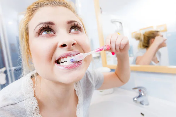 Woman brushing cleaning teeth closeup. Funny blonde girl with toothbrush in bathroom. Oral hygiene. Unusual wide angle view