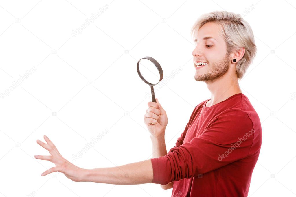 Narcissist, self absorption concept. Male holding magnifying glass looking at hands fingers nails obsessing about cleanliness, isolated on white
