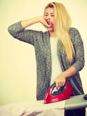 Ev hanımı sorunları, yorgunluk kavramı. Ütü masası duran demir elbise çok sahip uykulu esneme sıkılmış bir kadın. Parlak arka plan üzerinde atış stüdyo