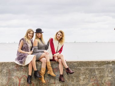 Üç modaya uygun kadın şık kıyafetler giyiyorlar. Tarz, moda, arkadaşlık konsepti.