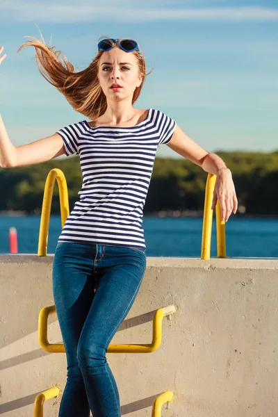 Sarışın genç kadın rahat tarzı taş duvar deniz arka planda karşı