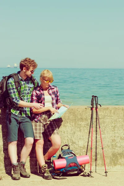 Adventure, summer, tourism active lifestyle. Young couple backpacker looking at map by seaside, plan their sightseeing