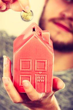 Ev tasarruf ve finans, ekonomi kavramı. Kumbara house, stüdyo ışık arka plan üzerinde atış şeklinde para madeni para koyarak adam