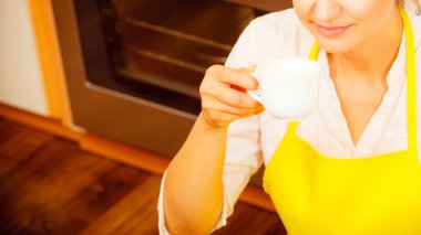 Kadın mutfakta kahve içme önlük. Ev hanımı kadın yere oturma rahatlatıcı.