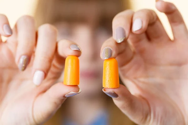 Woman holding protective ear plugs. Getting rid on noise in loud place, hearing protection concept.