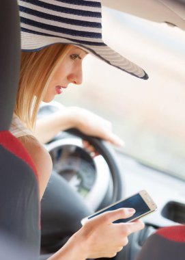 Dikkati dağılmış sürücü. Genç çekici kadın araba kullanırken cep telefonu kullanıyor, mesaj yazıyor ya da okuyor..