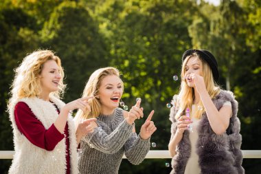 Tatil eğlencesi, arkadaşlık konsepti. Kadın arkadaşlar dışarıda sabun köpüğü üflerken eğleniyorlar..