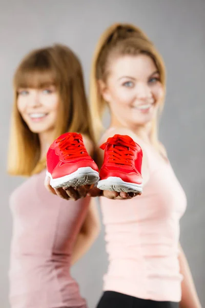 Dos Mujeres Sonrientes Deportivas Felices Que Presentan Zapatillas Deportivas Zapatos —  Fotos de Stock