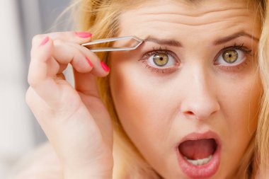 Kaşlarını yolan bir kadın cımbızla tükendi. Yüzünün bir kısmını kapatıyordu. Cımbızla yüz kıllarını kesen kız...