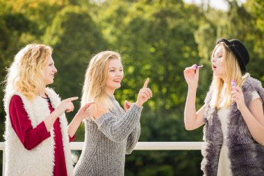 Tatil eğlencesi, arkadaşlık konsepti. Kadın arkadaşlar dışarıda sabun köpüğü üflerken eğleniyorlar..