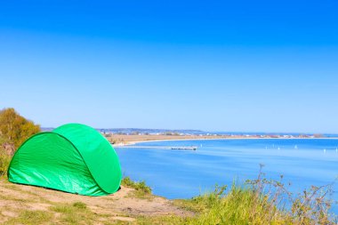 Turizm ve Rekreasyon. Çayır su deniz göl tarafından çevrili doğal alanda küçük yeşil çadır.