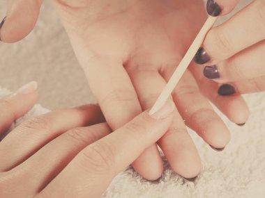 Tırnak bakımı, güzellik sağlık kaplıcası konsepti. Manikürden önce tırnaklarını hazırlayan kadın güzellik uzmanı, tahta sopa kullanarak tırnak etlerini geri itiyor.