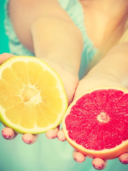 Halfs of yellow and red grapefruit citrus fruit in female hands closeup. Woman dietician recommend healthy diet nutrition.