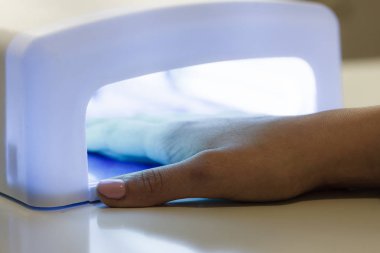 Kadın elinde uv lamba jel hibrid manikür çivi üzerinde kurutma yol açtı. Güzellik sağlık spa tedavi kavramı.