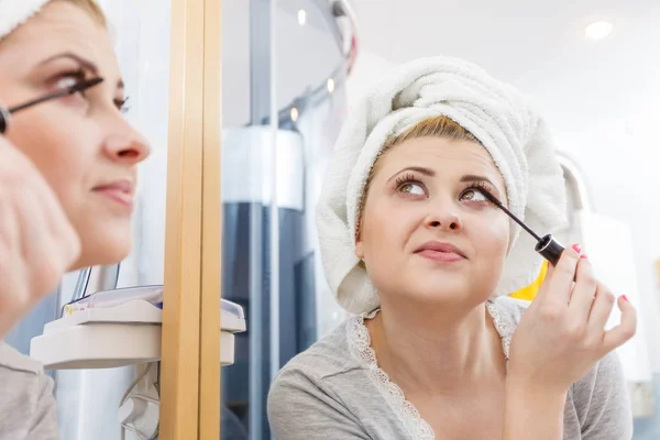 外表和概念组成 女人在浴室毛巾头上裹着在睫毛上涂睫毛膏 — 图库照片
