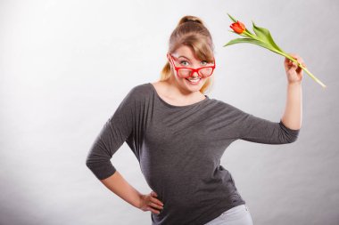 Bahar zamanı. Delilik ve eğlenceli bir kavram. Oynak mutlu kız çiçek ile oynuyor. Lale ile deli rakamlar yapma sevinçli gülümseyen komik pozitif kadın kişi.