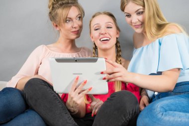 Eğleniyor koltukta oturan kadınlar akıllı dijital pc tablet modern cihaz kullanarak internette sörf