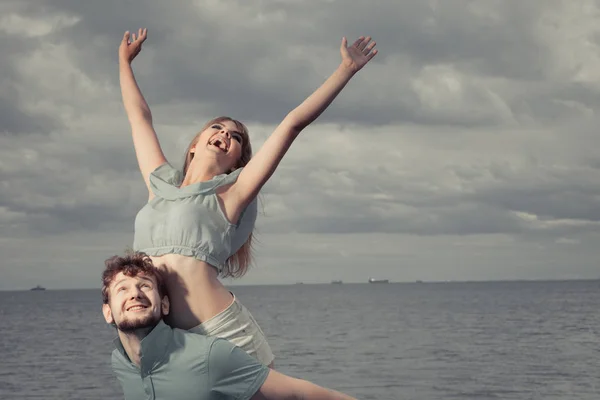 Summer happiness concept. Woman and man young couple in love playing sharing free time having fun outdoor on sea pier sky background