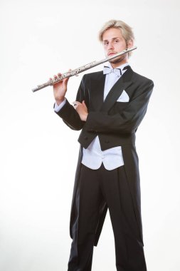 Klasik müzik eğitimi konsepti. Erkek flütçü müzisyen flüt çalıyor. Paltolu genç adam enstrüman tutuyor.