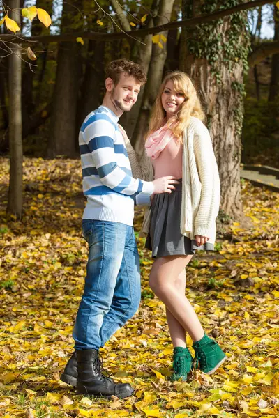 Mevsim, mutluluk ve insan konsepti. İlişkiler ve duygular. Sonbahar parkında dinlenen genç çift güneşli bir günde romantik bir buluşmanın tadını çıkarıyor..