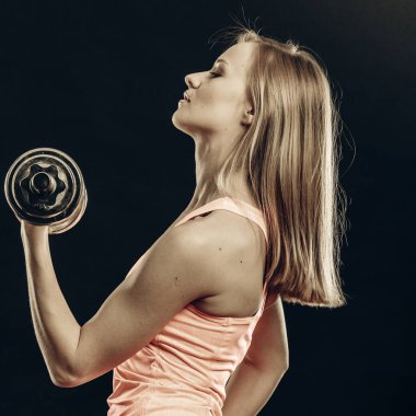 Vücut geliştirme. Güçlü kadın dumbbells ile egzersiz uygun. Siyah arka plan üzerine ağırlık studio kaldırma kaslı sarışın kız vurdu
