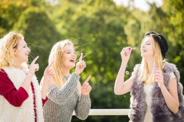 Tatil eğlencesi, arkadaşlık konsepti. Kadın arkadaşlar dışarıda sabun köpüğü üflerken eğleniyorlar..