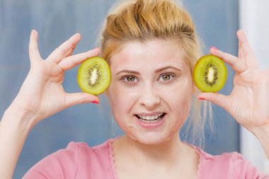 Yüz cilt ve vücut bakımı, vitamin iyi cilt tedavi ev concept. Kivi meyve tutan yüzünde maske akasındaki jel olan genç kadın.